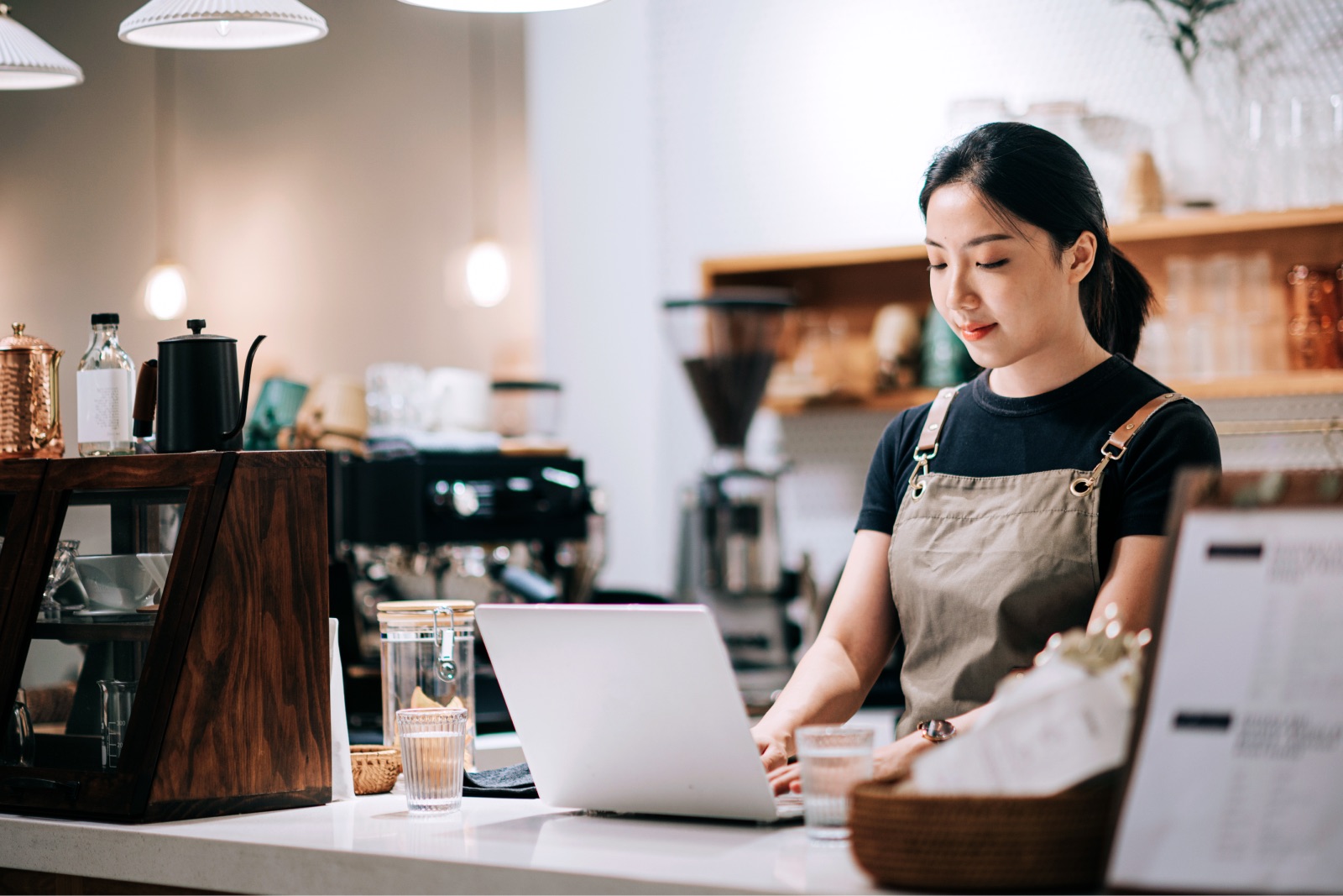 カフェのカウンターでノートPCを操作する店員