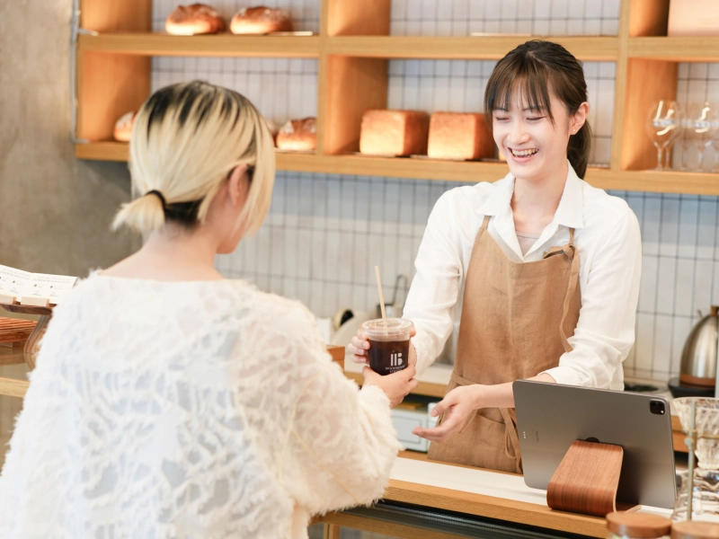 カウンターで従業員とお客さまが商品のやりとりをしているカフェの写真