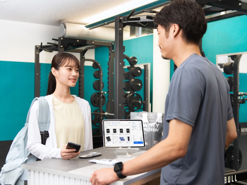 カウンターで従業員とお客さまが会計をしているフィットネスクラブの写真