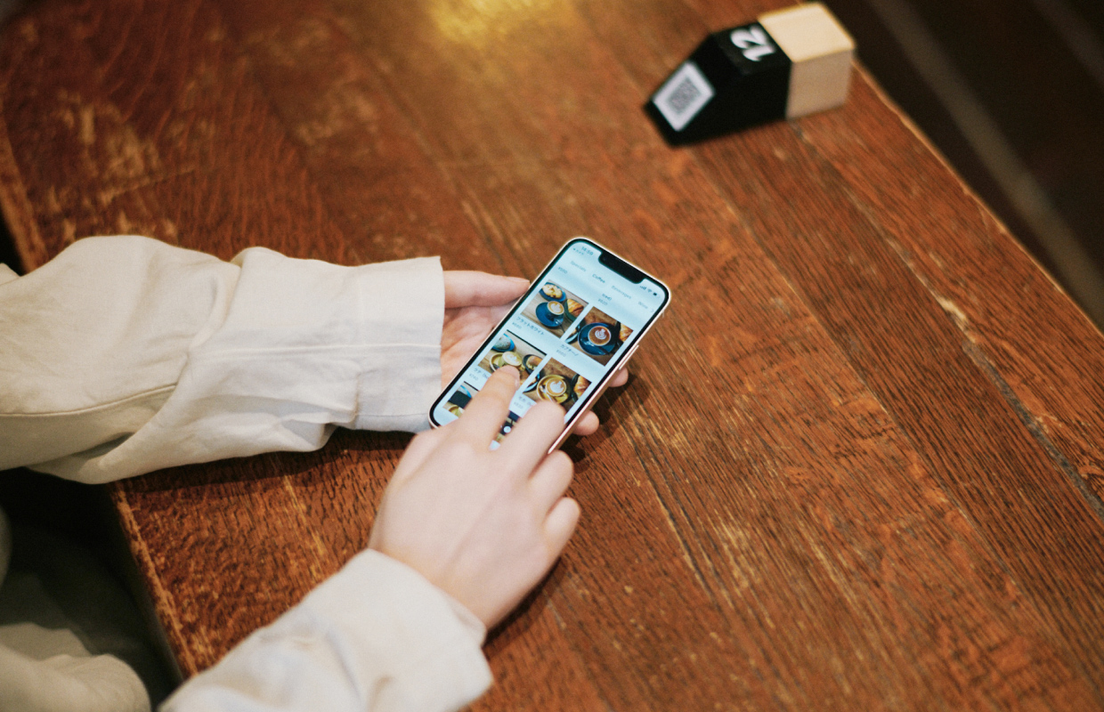 テーブルに置かれた QR ポップとスマホでメニューを見るお客さま